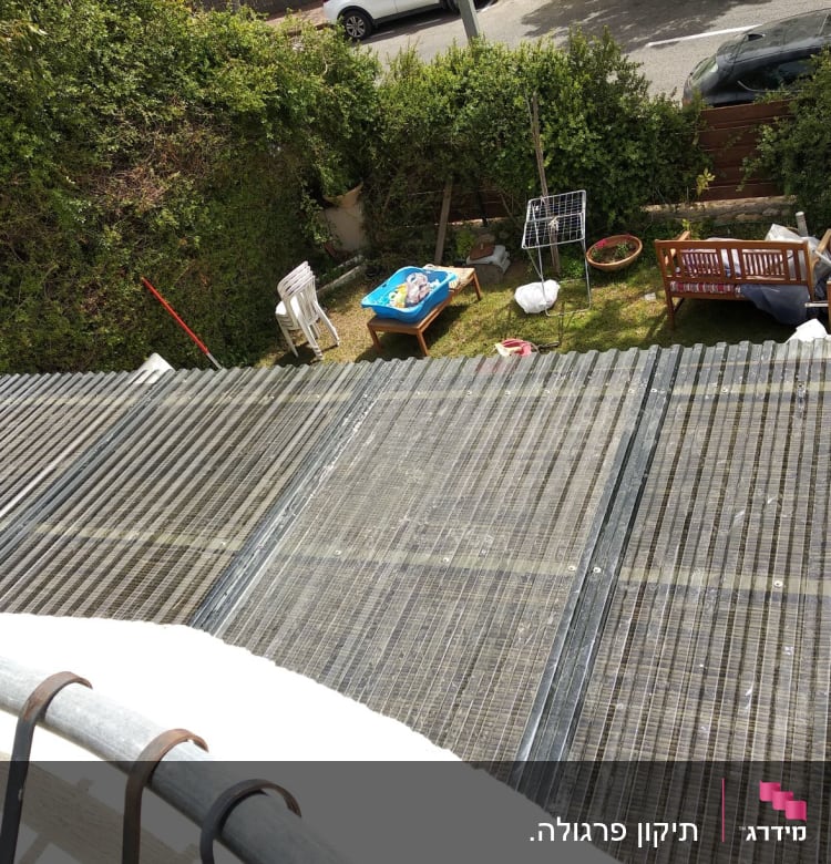 גג פלסטיק שקוף מעל גינה עם ריהוט עץ